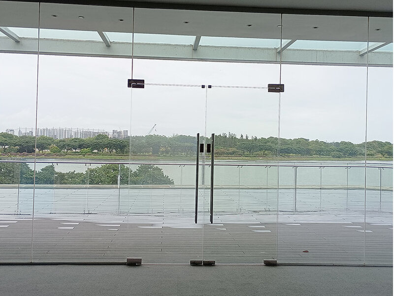 Before: Frameless glass manual swing doors with fixed glass panels — no steel structure for door automation